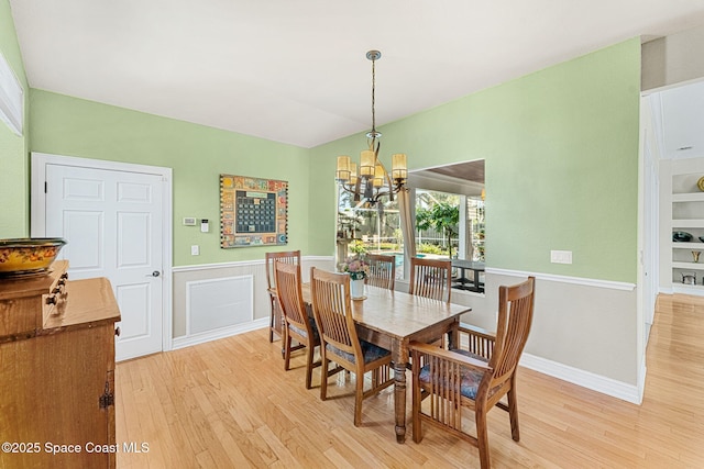 dining area with built in features, a chandelier, and light hardwood / wood-style floors