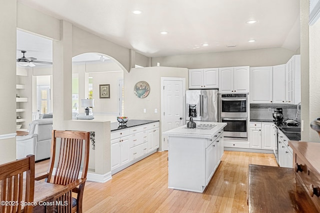 kitchen featuring white cabinetry, ceiling fan, appliances with stainless steel finishes, tasteful backsplash, and a center island