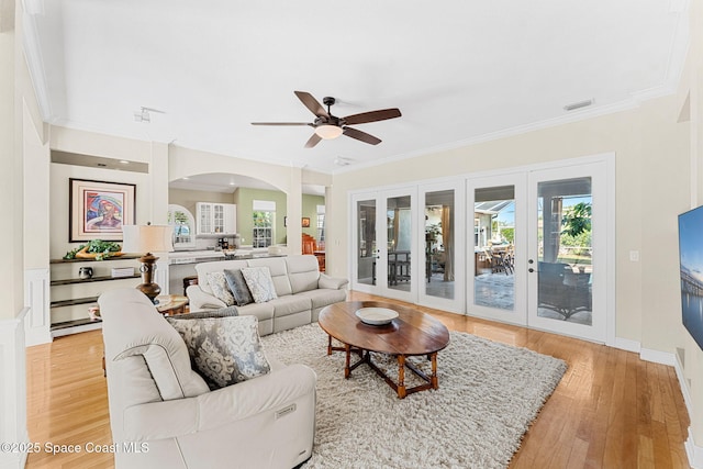 living room with ceiling fan, hardwood / wood-style floors, ornamental molding, and french doors