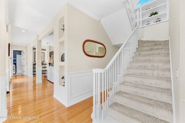 staircase with wood-type flooring, built in features, and crown molding