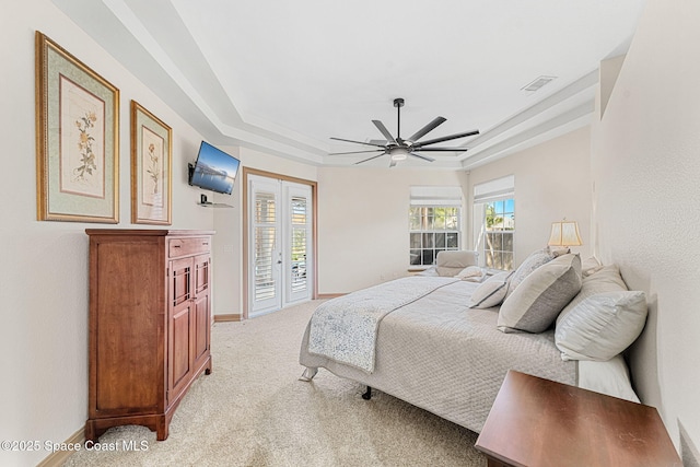 carpeted bedroom featuring ceiling fan, a raised ceiling, and access to outside