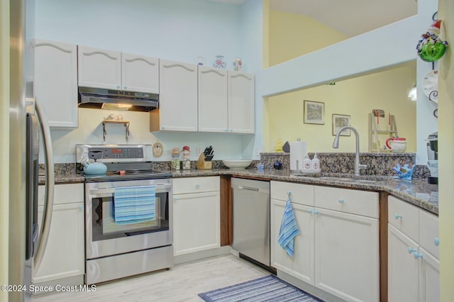 kitchen featuring white cabinetry, sink, stainless steel appliances, kitchen peninsula, and dark stone countertops