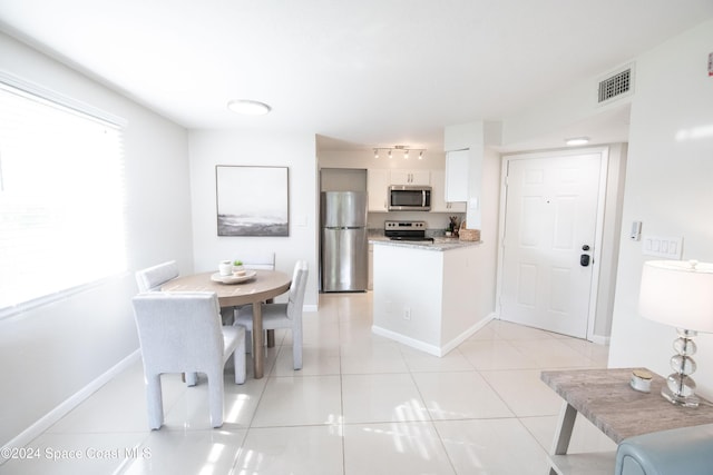 kitchen with light tile patterned floors, white cabinetry, and appliances with stainless steel finishes