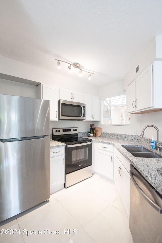 kitchen featuring light stone countertops, appliances with stainless steel finishes, sink, light tile patterned floors, and white cabinets