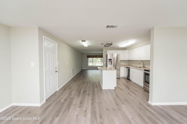 kitchen with a kitchen island, sink, white cabinetry, light hardwood / wood-style flooring, and stainless steel appliances