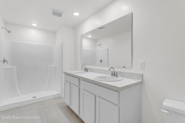 bathroom featuring a shower, vanity, toilet, and tile patterned flooring