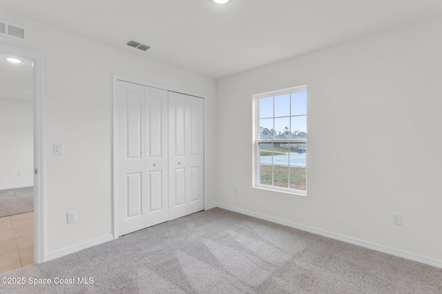 unfurnished bedroom with a closet and light colored carpet