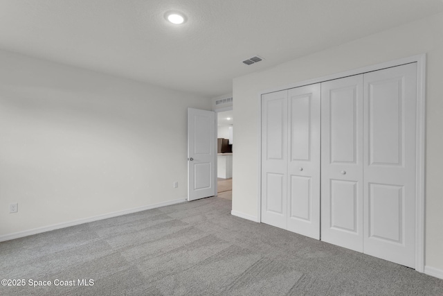 unfurnished bedroom featuring light colored carpet and a closet