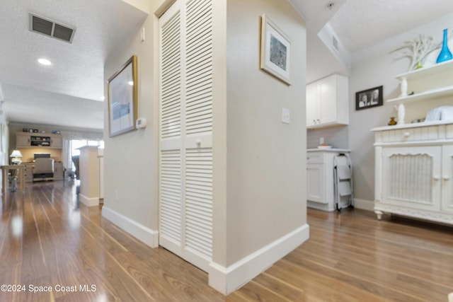 hallway featuring a textured ceiling and light hardwood / wood-style floors