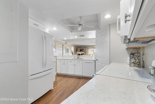 kitchen featuring white appliances, white cabinets, a raised ceiling, ornamental molding, and dark hardwood / wood-style flooring