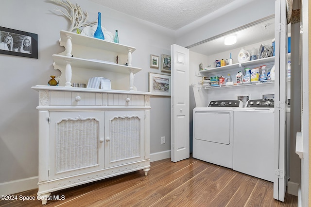 clothes washing area featuring hardwood / wood-style floors, a textured ceiling, and washing machine and clothes dryer