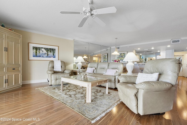 living room with ceiling fan, light wood-type flooring, ornamental molding, and a textured ceiling