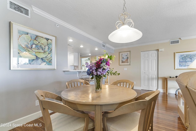 dining space with dark hardwood / wood-style floors, ornamental molding, and a textured ceiling