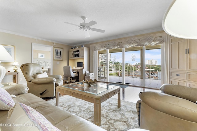 living room featuring ceiling fan, light wood-type flooring, ornamental molding, and a textured ceiling