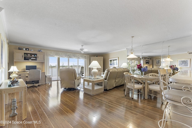 living room with hardwood / wood-style flooring, ceiling fan, a textured ceiling, and ornamental molding