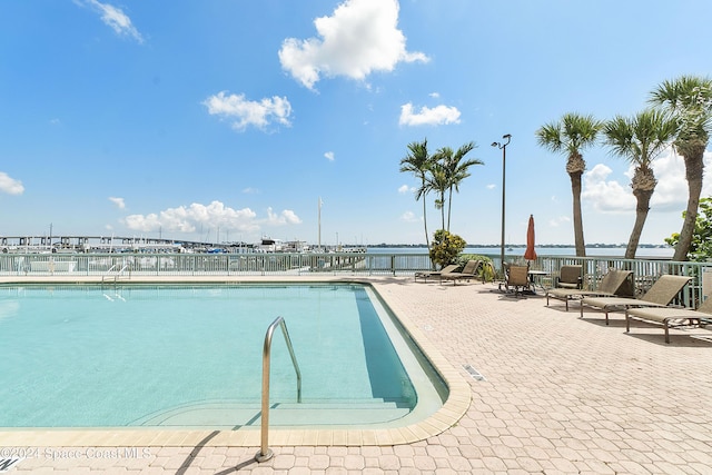 view of pool with a water view and a patio area