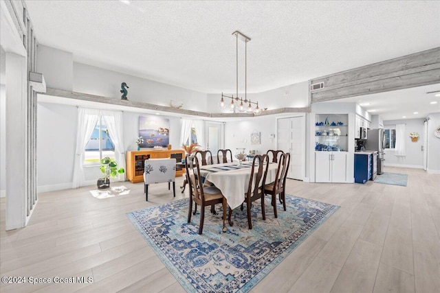 dining room with light hardwood / wood-style flooring and a textured ceiling