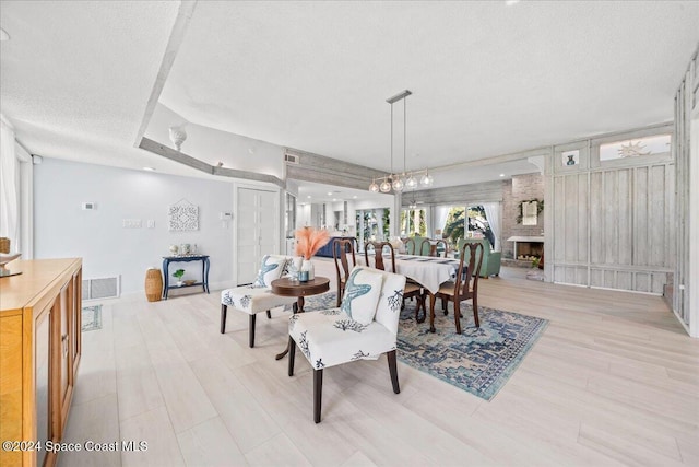 dining room with a chandelier, a textured ceiling, and a brick fireplace