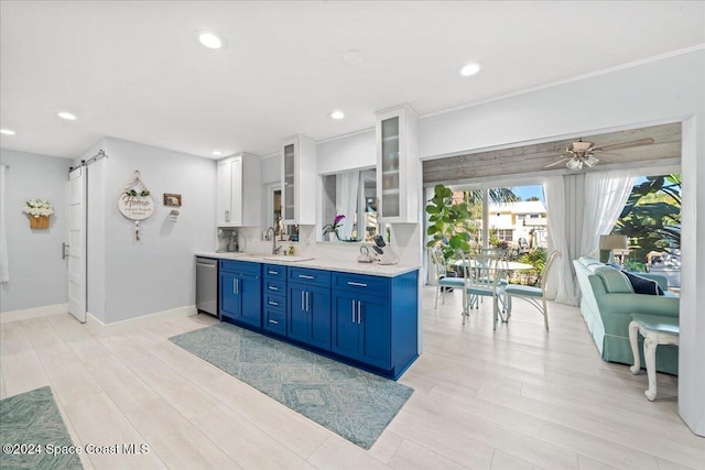 kitchen featuring ceiling fan, sink, stainless steel dishwasher, blue cabinets, and white cabinets