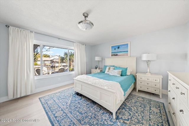 bedroom featuring a water view and a textured ceiling