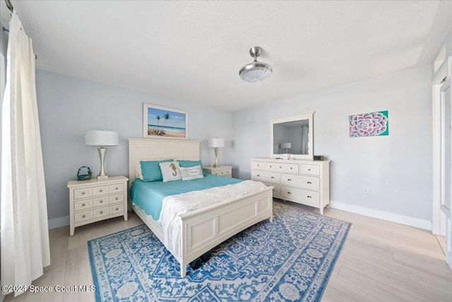 bedroom featuring a textured ceiling and light hardwood / wood-style flooring