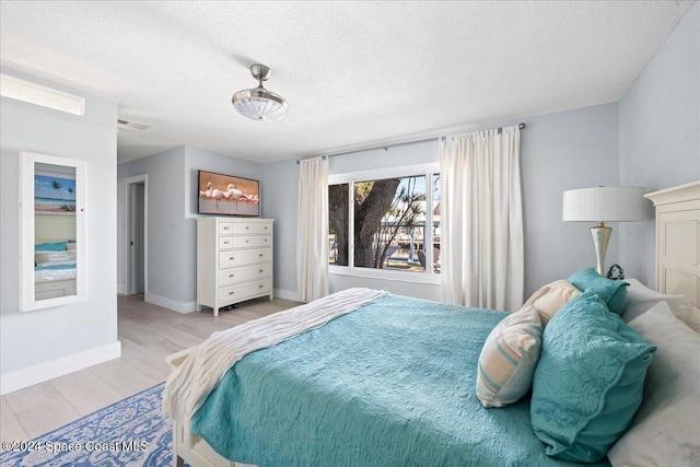 bedroom with a textured ceiling and light wood-type flooring