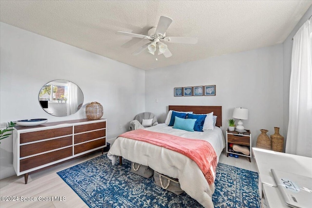 bedroom featuring ceiling fan, light hardwood / wood-style floors, and a textured ceiling