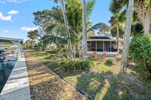 view of yard with a sunroom and a dock