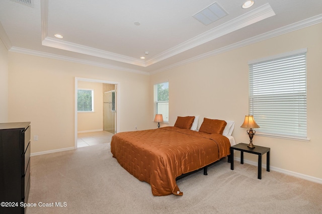 carpeted bedroom with a tray ceiling, ensuite bath, and ornamental molding