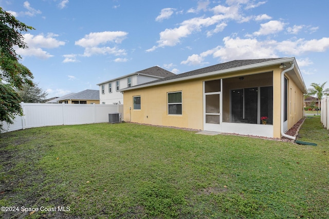 back of property with a sunroom, a yard, and cooling unit