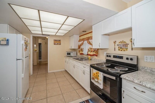 kitchen with light stone counters, white cabinets, light tile patterned flooring, and white appliances