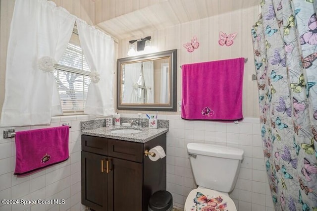 bathroom with vanity, toilet, walk in shower, and tile walls