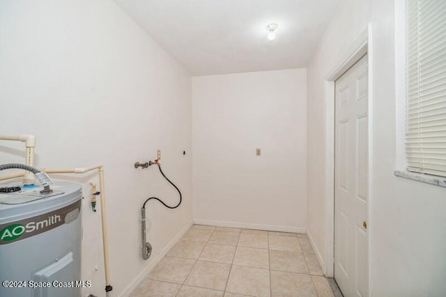 washroom with water heater, hookup for a washing machine, and light tile patterned floors