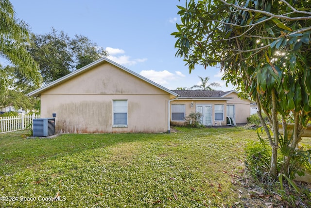 rear view of property with a lawn and cooling unit