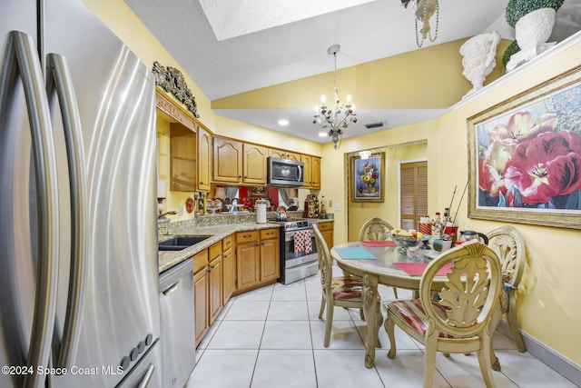 kitchen featuring pendant lighting, sink, vaulted ceiling, light tile patterned floors, and stainless steel appliances