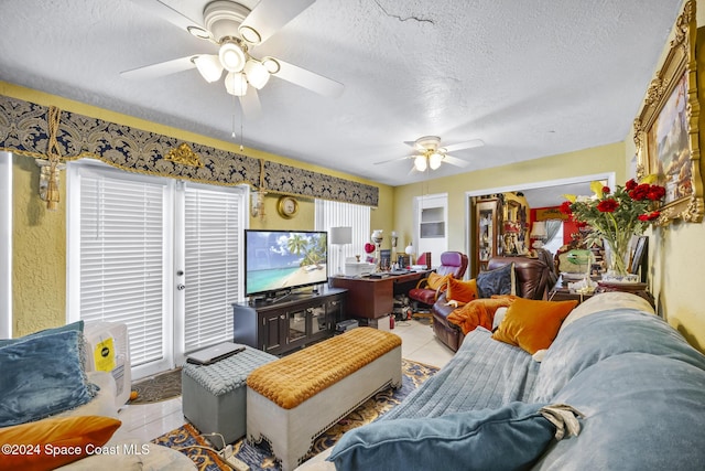 living room featuring ceiling fan, light tile patterned floors, and a textured ceiling