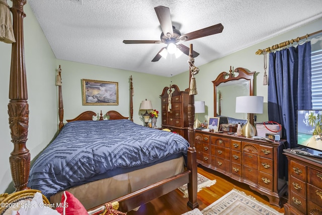 bedroom with ceiling fan, hardwood / wood-style floors, and a textured ceiling