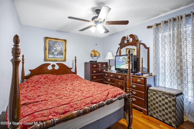 bedroom featuring ceiling fan, light hardwood / wood-style floors, and a textured ceiling