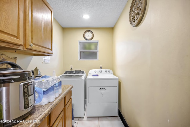 laundry room with cabinets, a textured ceiling, washing machine and dryer, and light tile patterned flooring