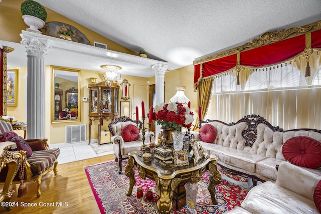 living room with wood-type flooring, ornate columns, a textured ceiling, and vaulted ceiling