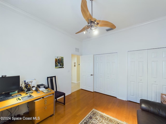 office space featuring ceiling fan, light hardwood / wood-style floors, a towering ceiling, and crown molding