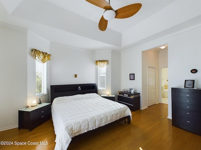 bedroom with a raised ceiling, ceiling fan, hardwood / wood-style floors, and ornamental molding