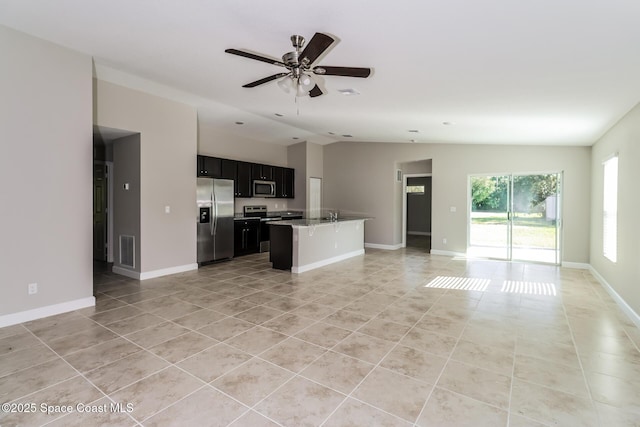 kitchen featuring vaulted ceiling, a kitchen island, appliances with stainless steel finishes, light tile patterned flooring, and ceiling fan