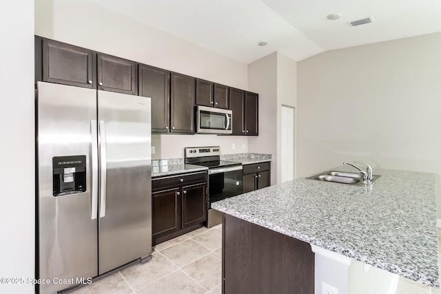 kitchen with lofted ceiling, dark brown cabinetry, sink, appliances with stainless steel finishes, and kitchen peninsula