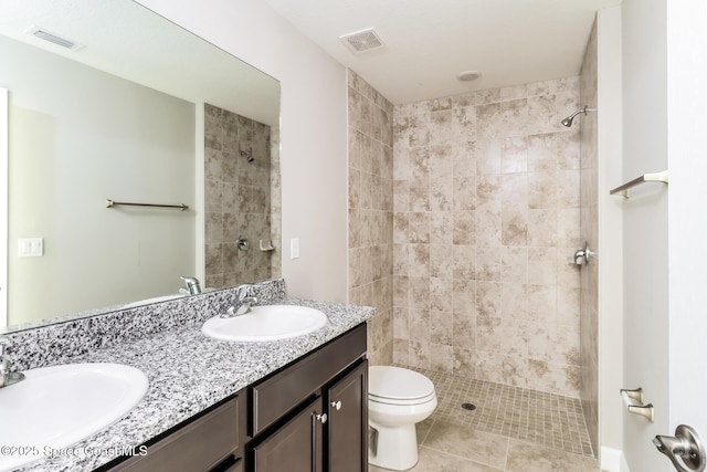 bathroom featuring tile patterned flooring, vanity, tiled shower, and toilet