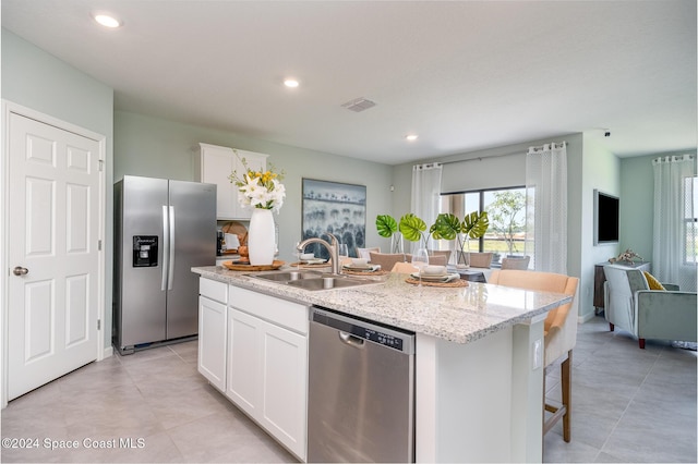 kitchen featuring stainless steel appliances, sink, white cabinetry, a kitchen breakfast bar, and a center island with sink