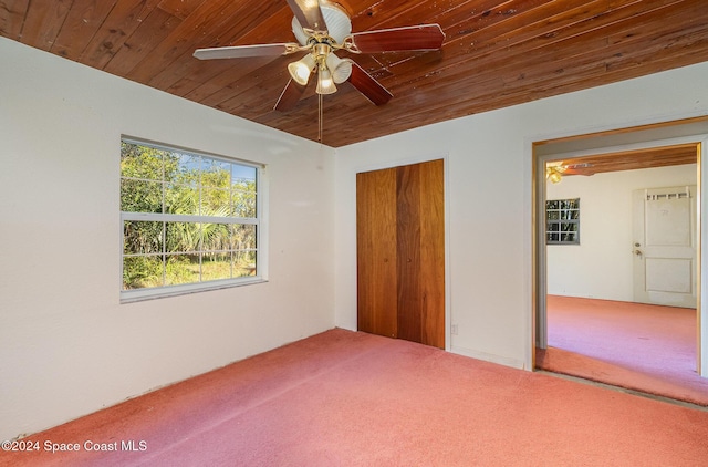 unfurnished bedroom with wood ceiling, vaulted ceiling, a closet, ceiling fan, and carpet