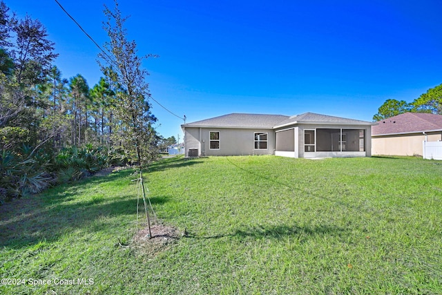 back of house with a sunroom, a lawn, and central AC