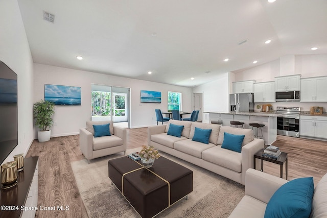 living room with light hardwood / wood-style flooring and vaulted ceiling