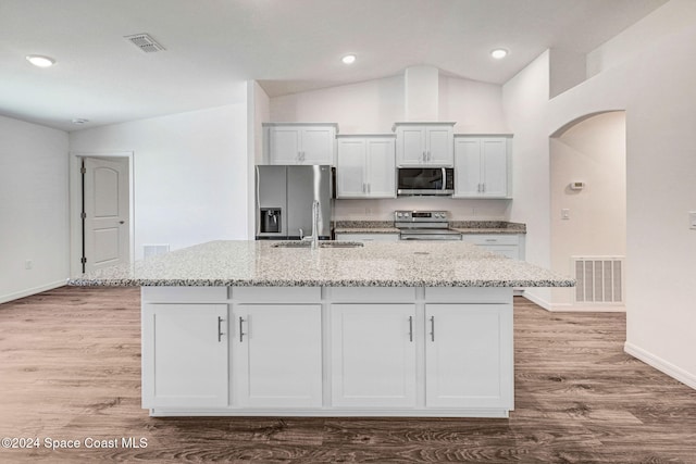 kitchen featuring white cabinets, stainless steel appliances, a kitchen island with sink, and lofted ceiling